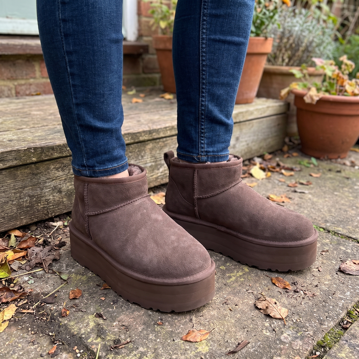 Brown mini platform ankle boots styled with jeans on a garden step