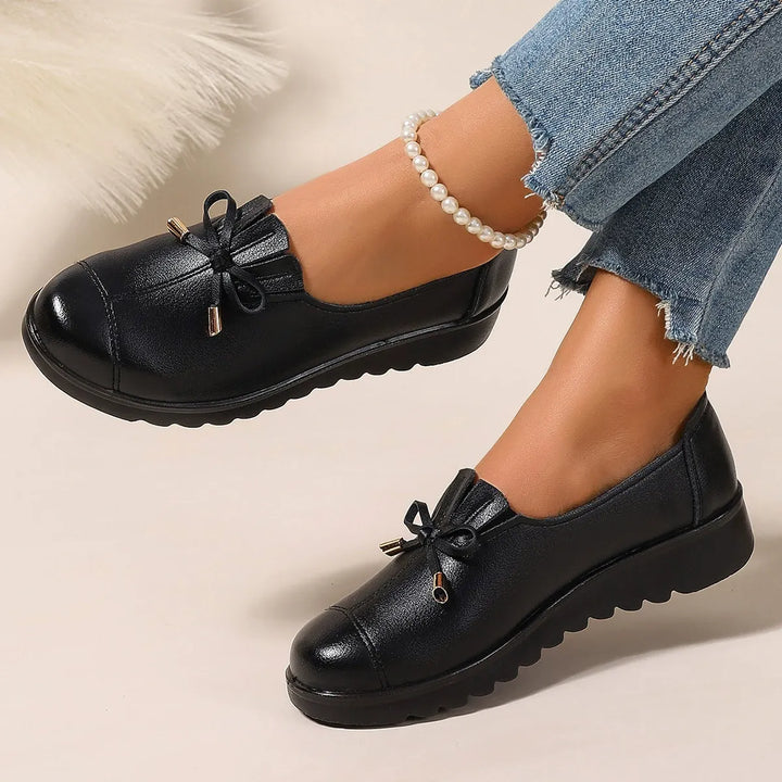 Black round toe loafers with bow, worn with cuffed jeans and a pearl anklet