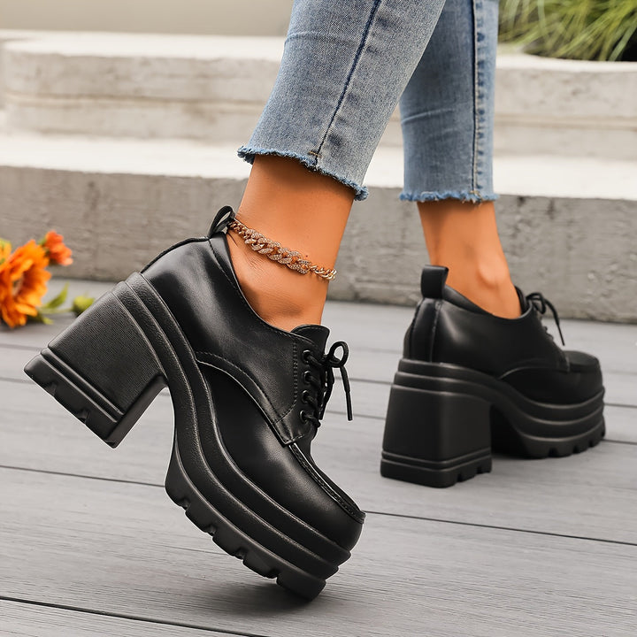 Black platform Oxford shoes with thick block heel, side view worn with jeans