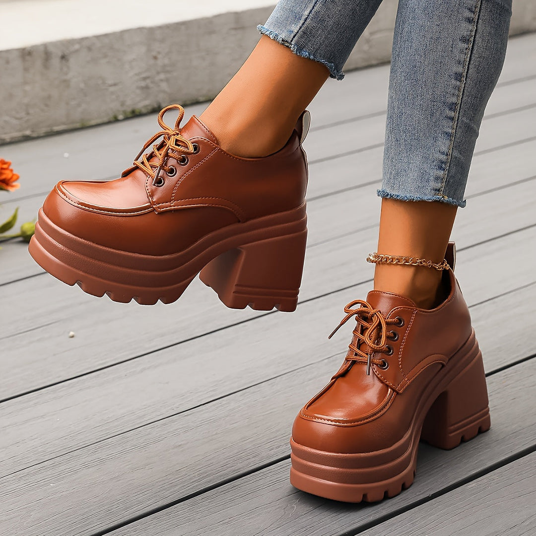 Brown lace up platform Oxford shoes with thick block heel, crossed legs in jeans
