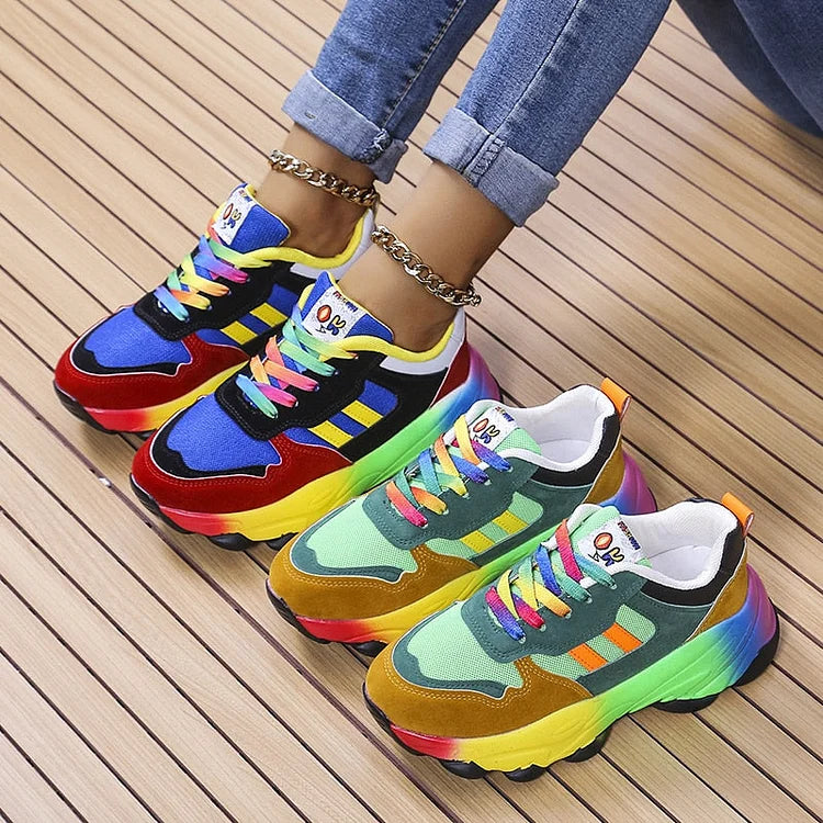 Two pairs of colorful lace up sneakers in blue and green tones on a wood floor