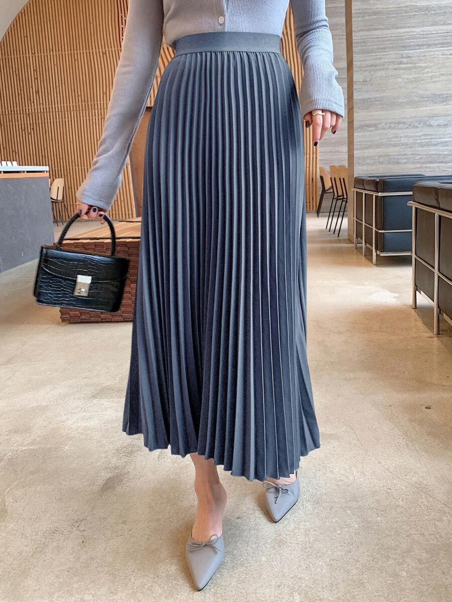 Fine pleated maxi skirt styled with a black structured handbag and gray flats