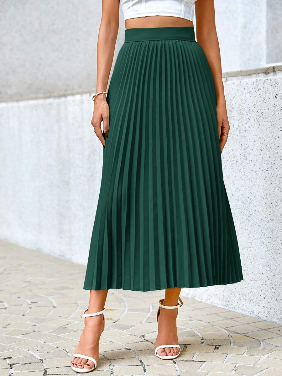 Green pleated midi skirt standing view showing the full length and wide hem