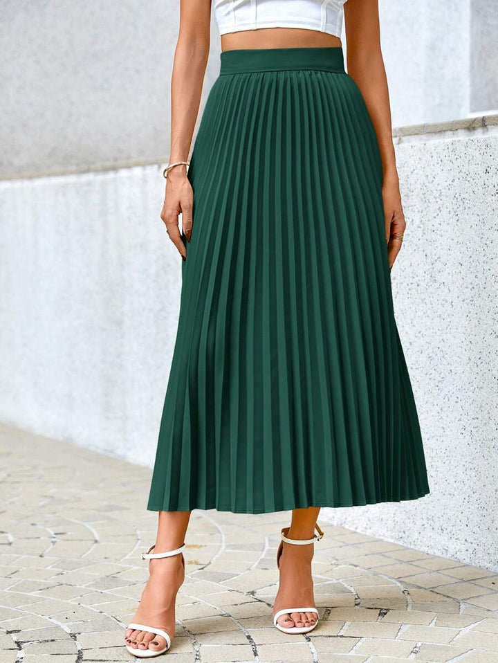 Green pleated midi skirt standing view showing the full length and wide hem