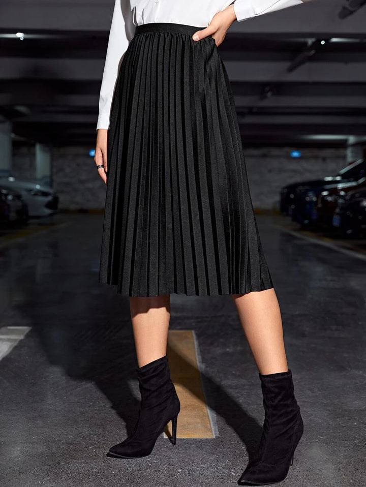 Back view of the black pleated midi skirt with a white long sleeve top