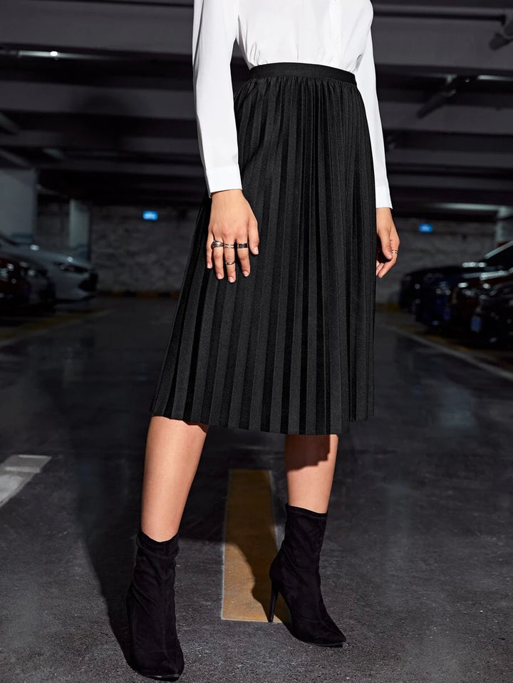 Black high waist pleated skirt styled with a white top and heeled booties