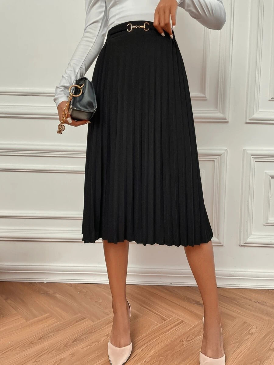 Black high waisted pleated skirt worn with a mini bag and pale top