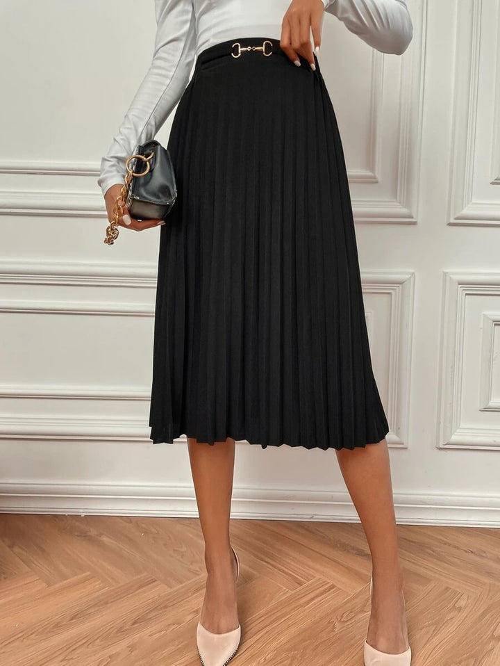 Black high waisted pleated skirt worn with a mini bag and pale top