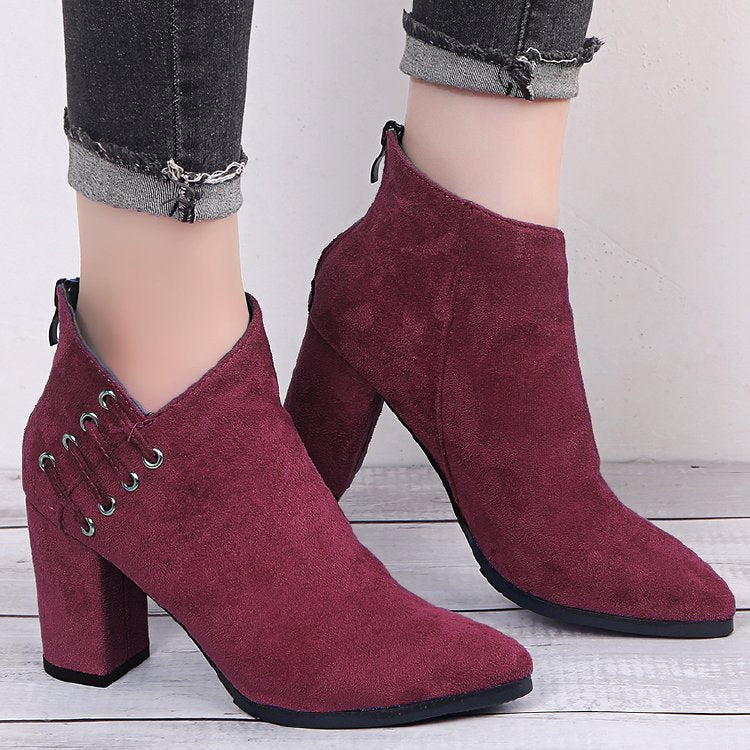 Burgundy suede-look ankle boots with eyelet lacing worn on a wooden floor