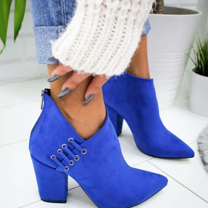 Hand pulling on a royal blue ankle boot with back zip and lace detail