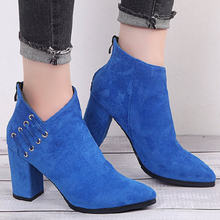 Pair of royal blue block heel booties worn with cuffed gray pants