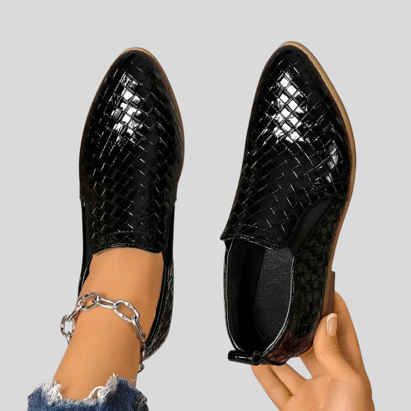 Black woven pointed toe ankle booties seen from the front with a hand holding one bootie
