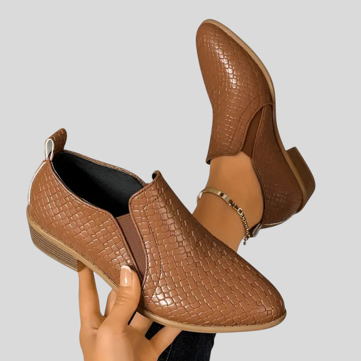 Brown woven ankle booties from behind, one held up to show the heel and pull-on back