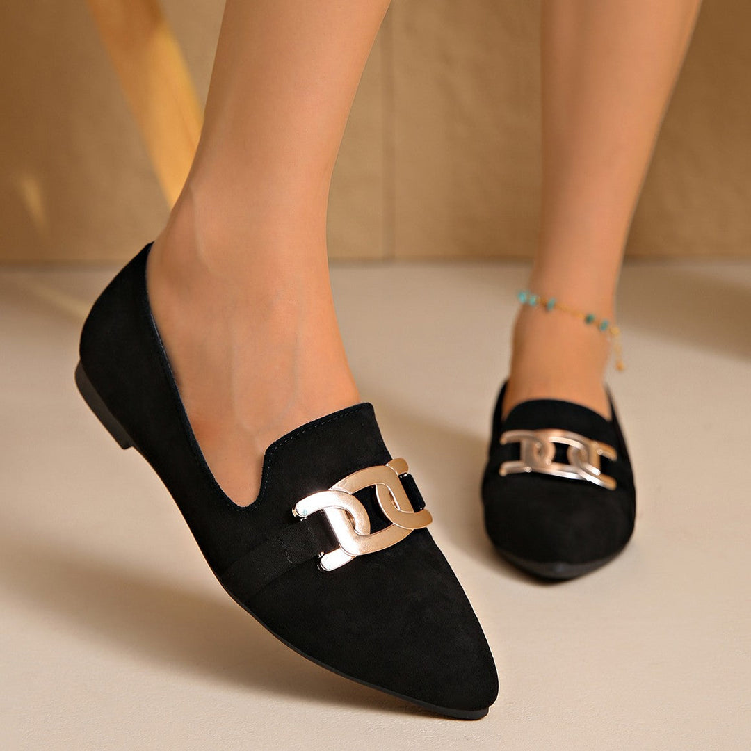 Black pointed toe flats worn with a beaded anklet, angled view