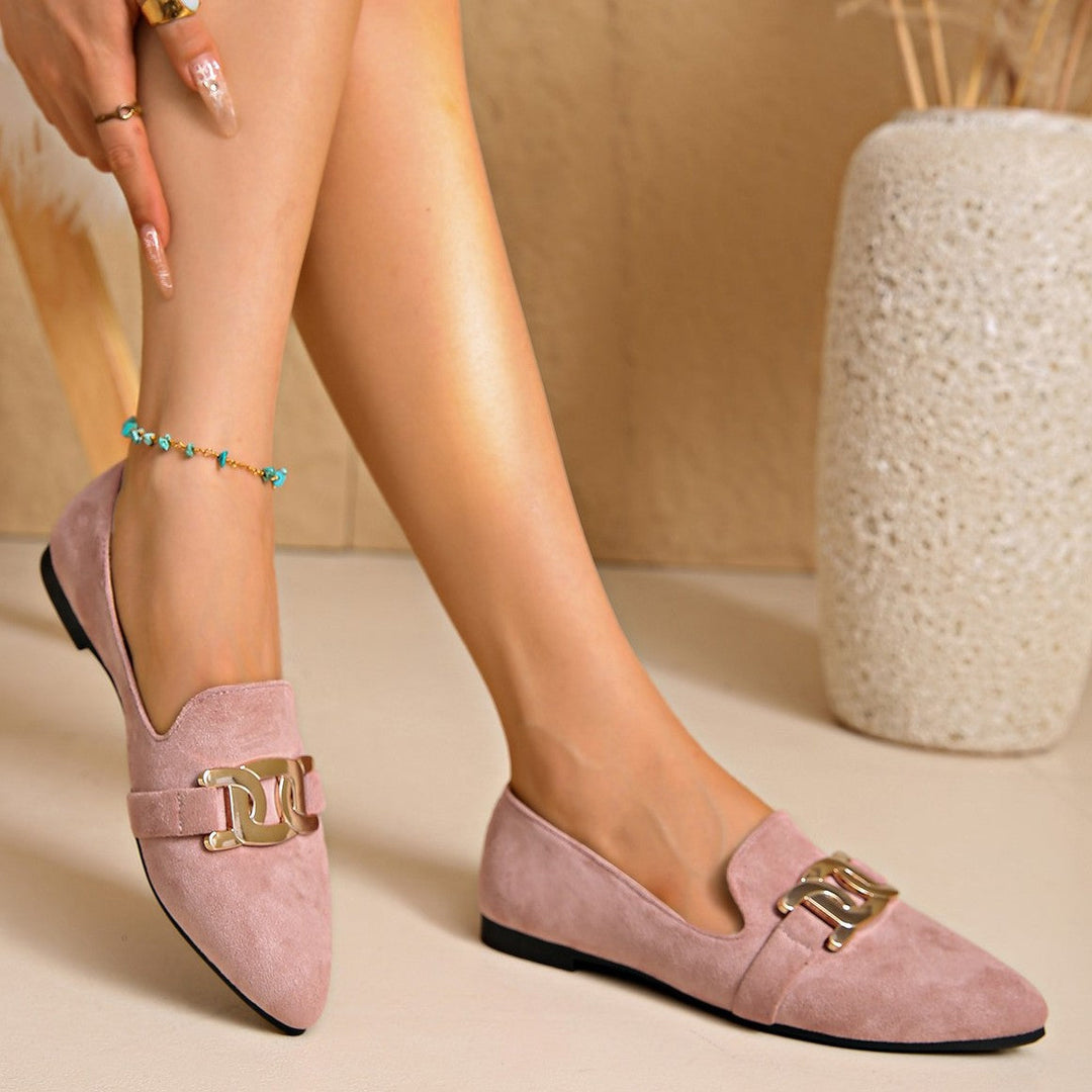 Dusty pink flats worn with bare legs next to a vase