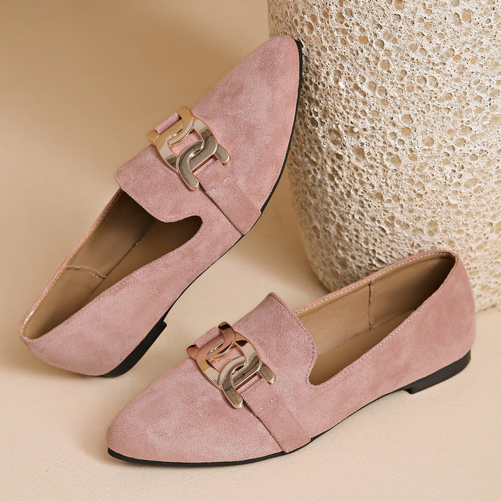 Dusty pink loafers staged beside a textured vase, chain detail facing front