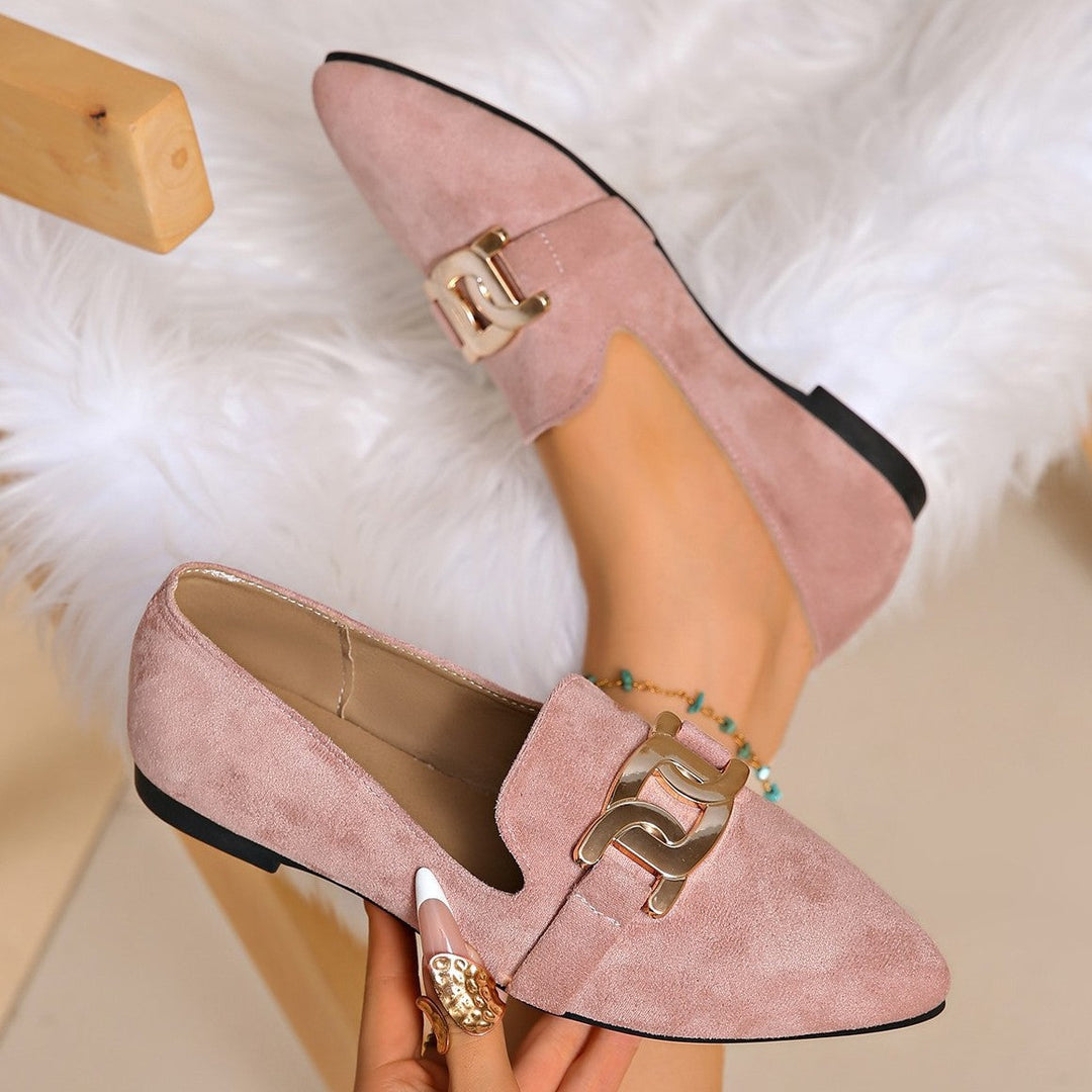 Dusty pink chain loafers displayed in hand on a white fur rug