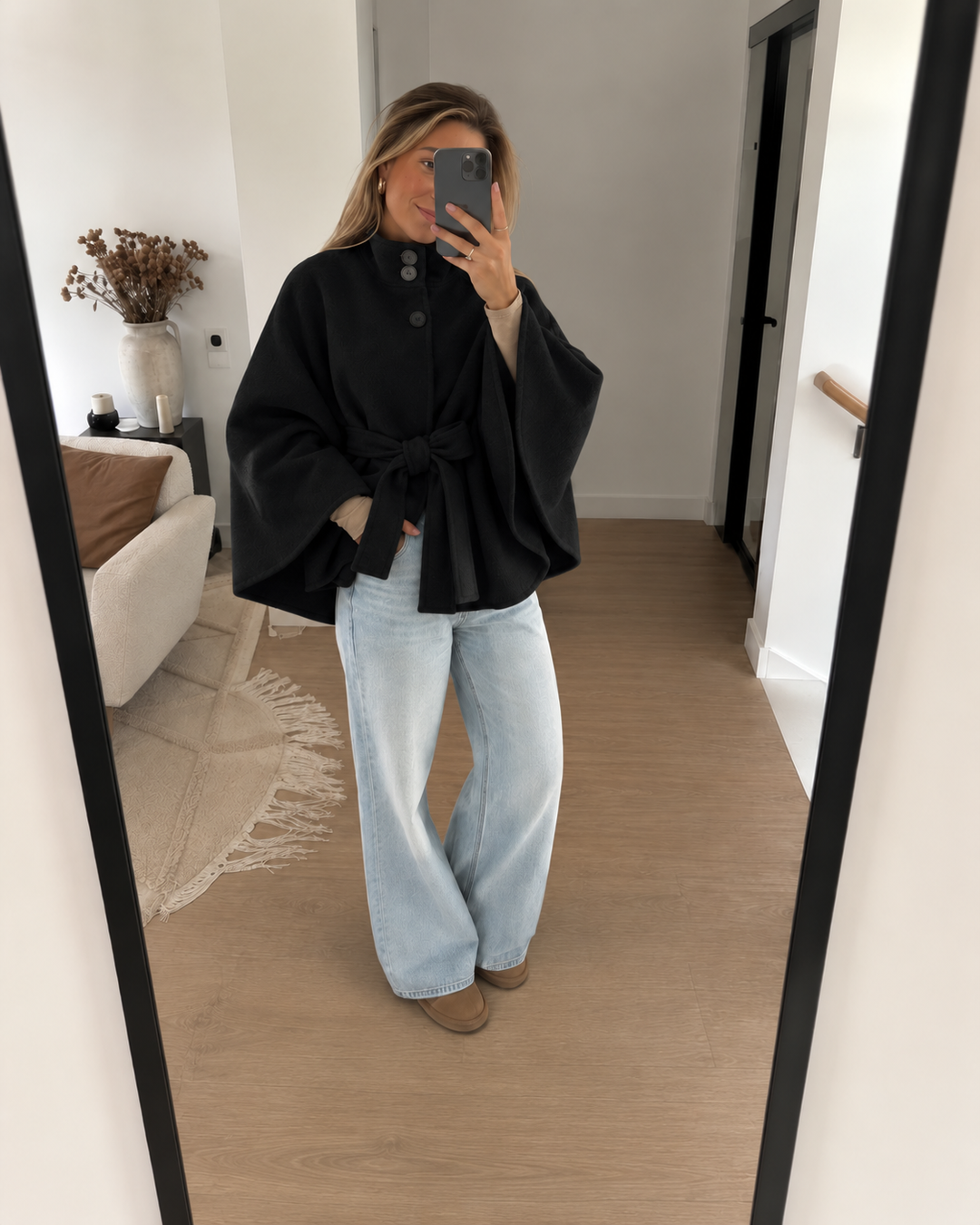 Mirror selfie in a black belted cape coat with light wide leg jeans