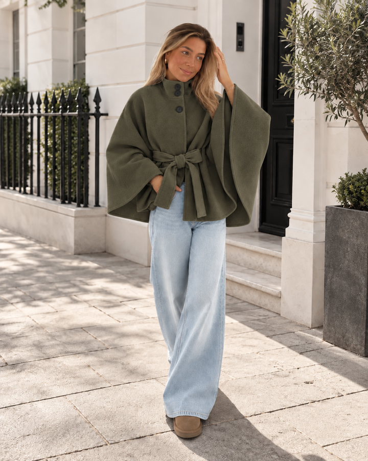 Olive green belted poncho coat worn on a street with light wide leg jeans