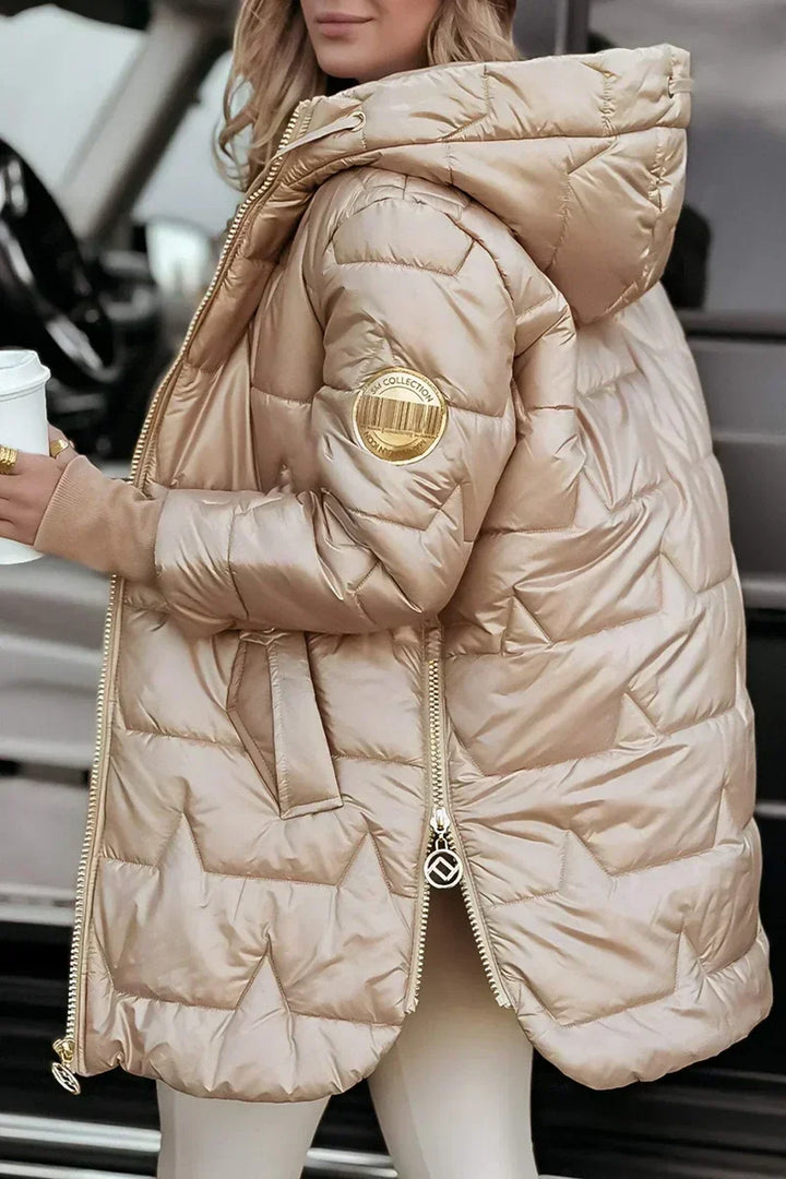 Beige hooded puffer coat with side zip detail, angled view holding coffee