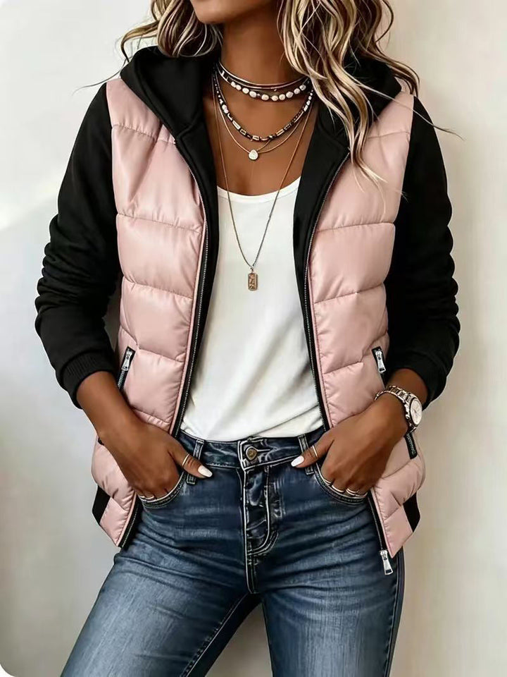 Pink puffer jacket with black knit sleeves, worn over a white top