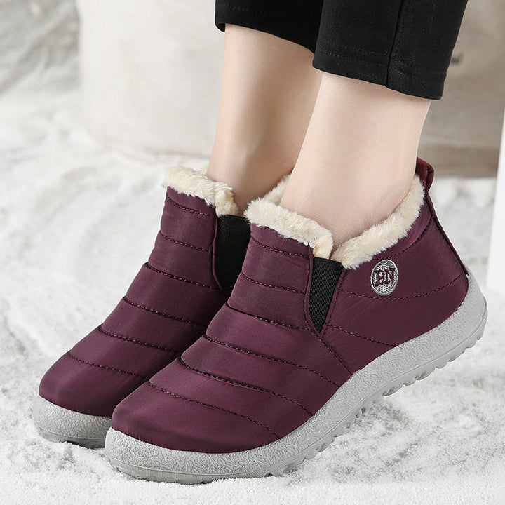 Plum slip on quilted ankle boot with faux fur trim, worn with black pants