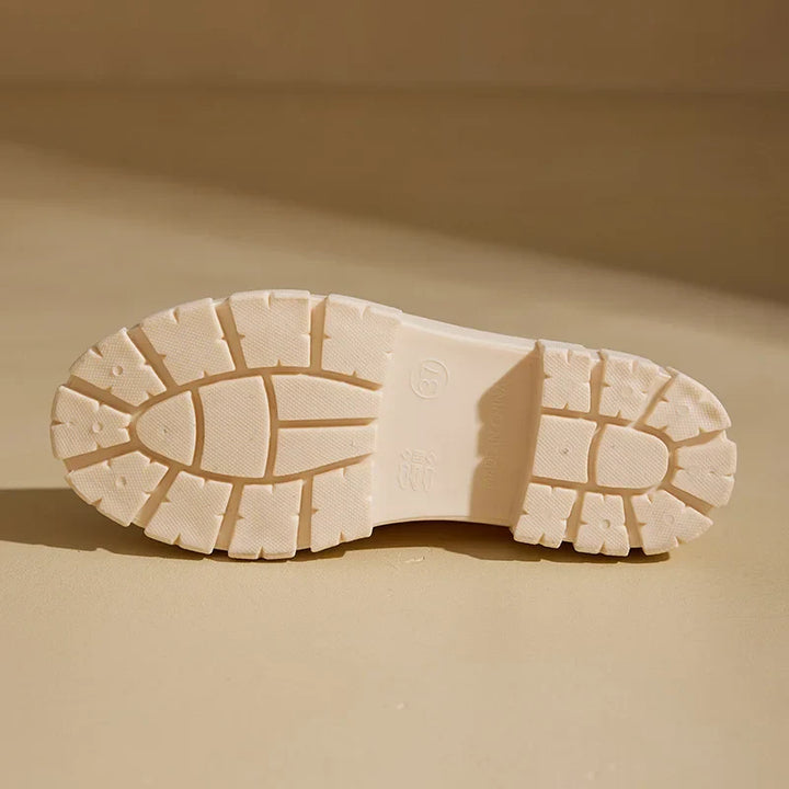 Cream chunky lug outsole of the Chelsea rain boot on a tan background