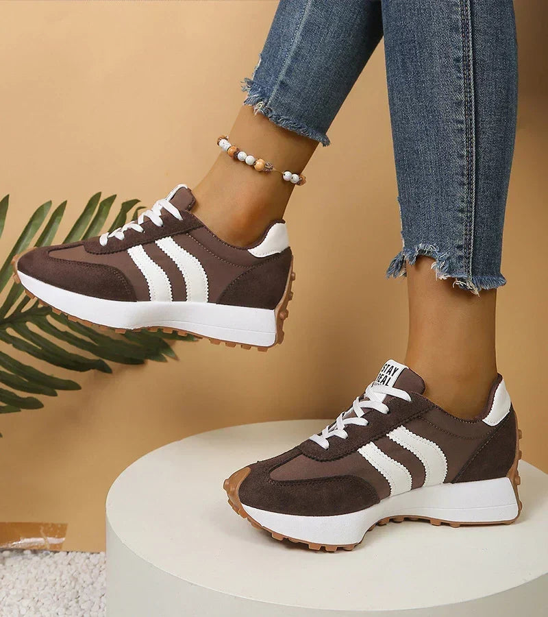 Pair of dark brown striped sneakers with white soles seen from a lower angle
