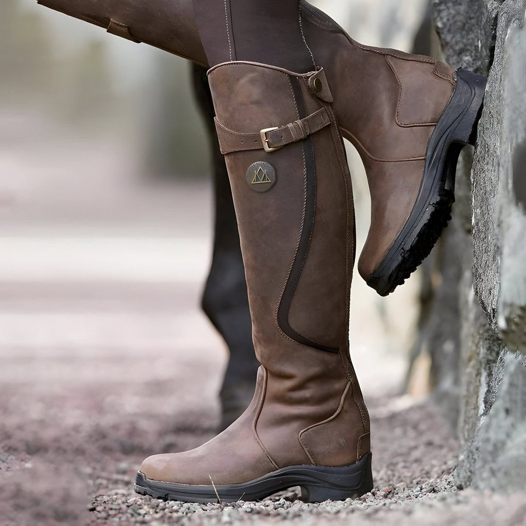 Women's dark brown knee high riding boots, side view on a model