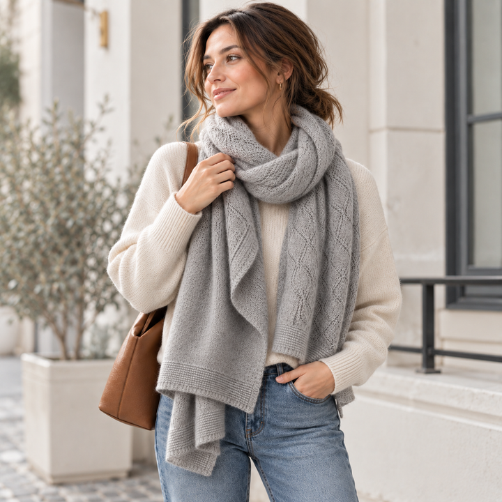 Woman wearing a light gray long knit scarf over a cream sweater and jeans