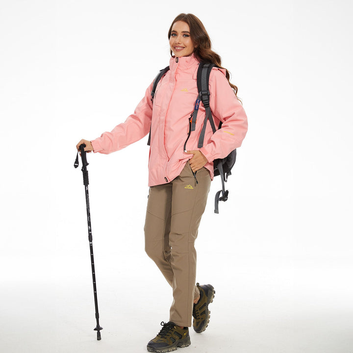 Hiker in the peach pink jacket with trekking poles and a backpack