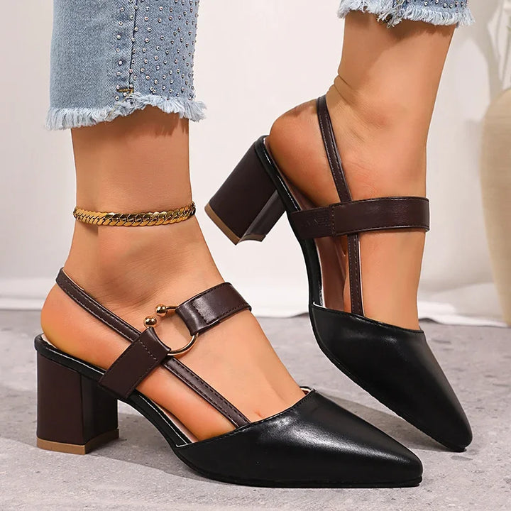 Side view of black slingback block heel pumps with buckle strap on a gray floor