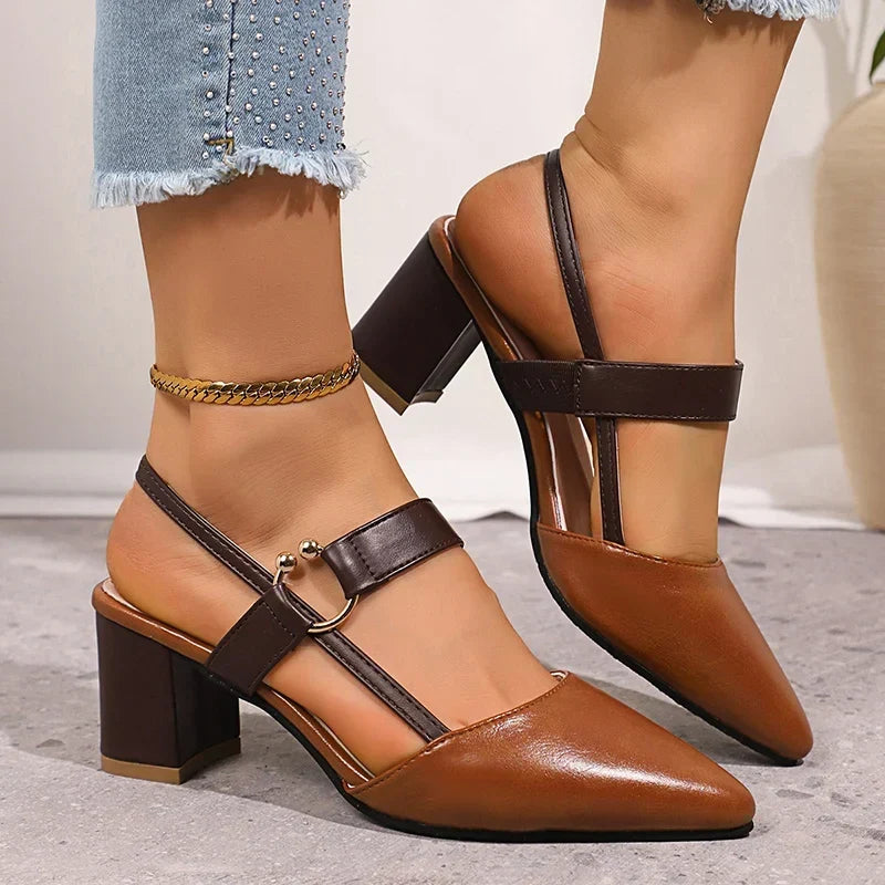 Side view of cognac slingback block heel pumps with buckle strap on a gray floor
