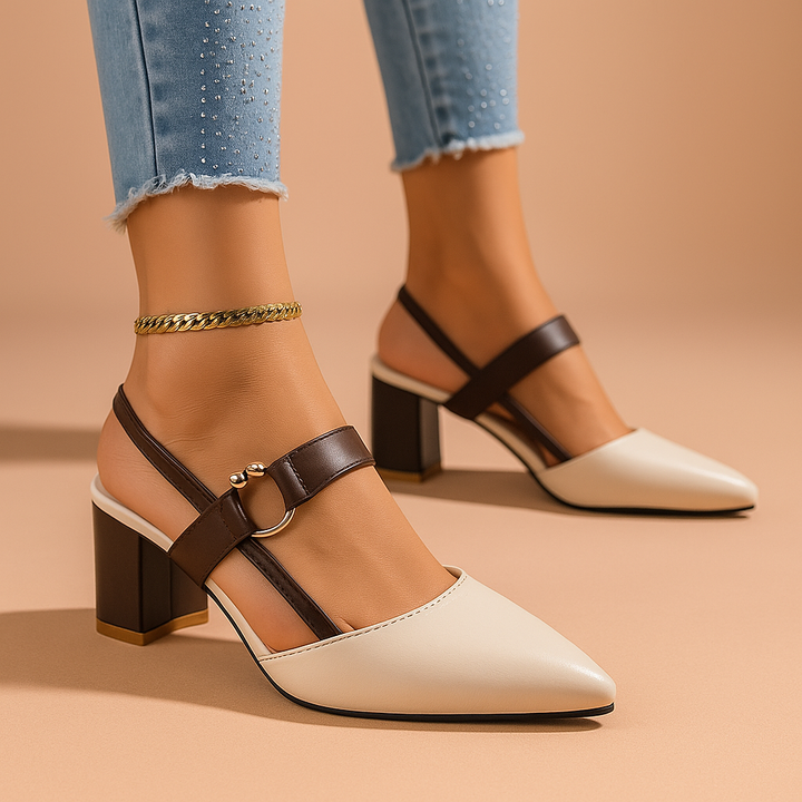 Cream block heel slingback pumps with brown straps worn with cuffed jeans on a peach backdrop