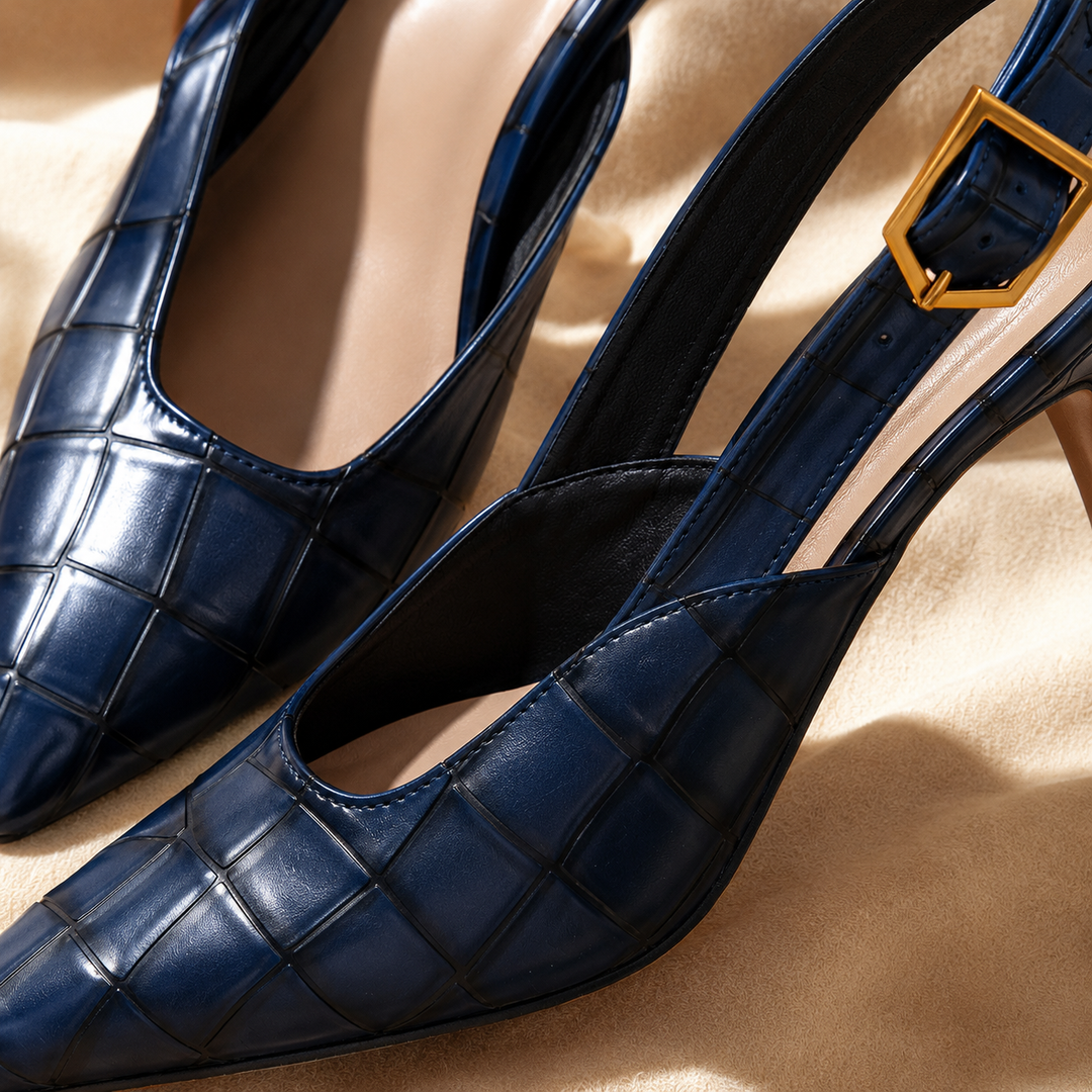 Close-up of the navy pointed toe slingback with gold-tone buckle strap