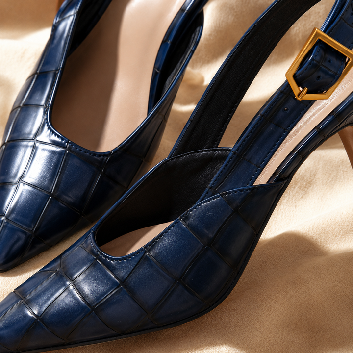 Close-up of the navy pointed toe slingback with gold-tone buckle strap