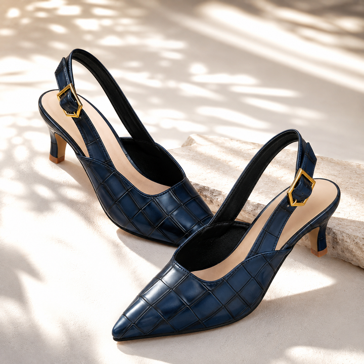 Pair of navy croc embossed slingback kitten heels on a light stone