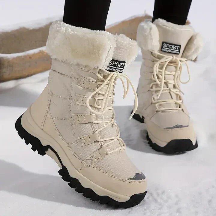 Women's snow boots in beige, lace up with faux fur cuff worn in the snow