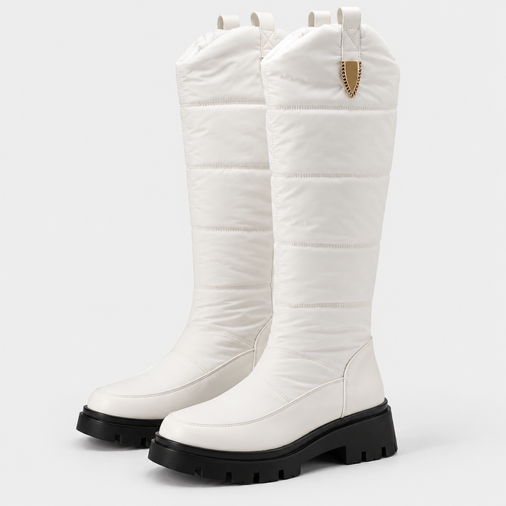 Pair of white knee high quilted snow boots with chunky black soles