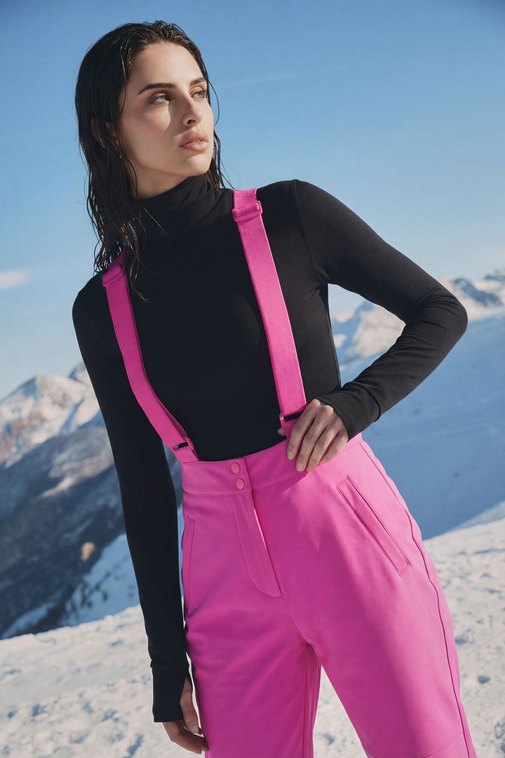 Close up of the fuchsia suspender straps over a black turtleneck
