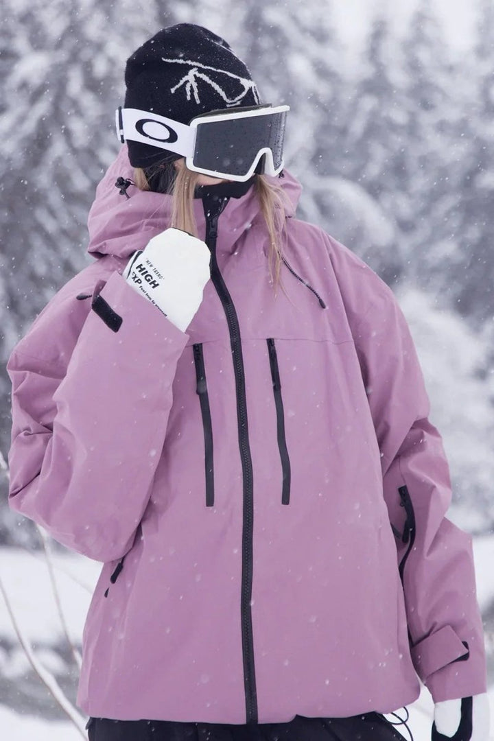 Woman in the pink oversized snowboard jacket adjusting her goggles