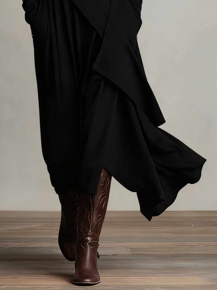 Detail of the black asymmetric hem flowing over brown leather boots