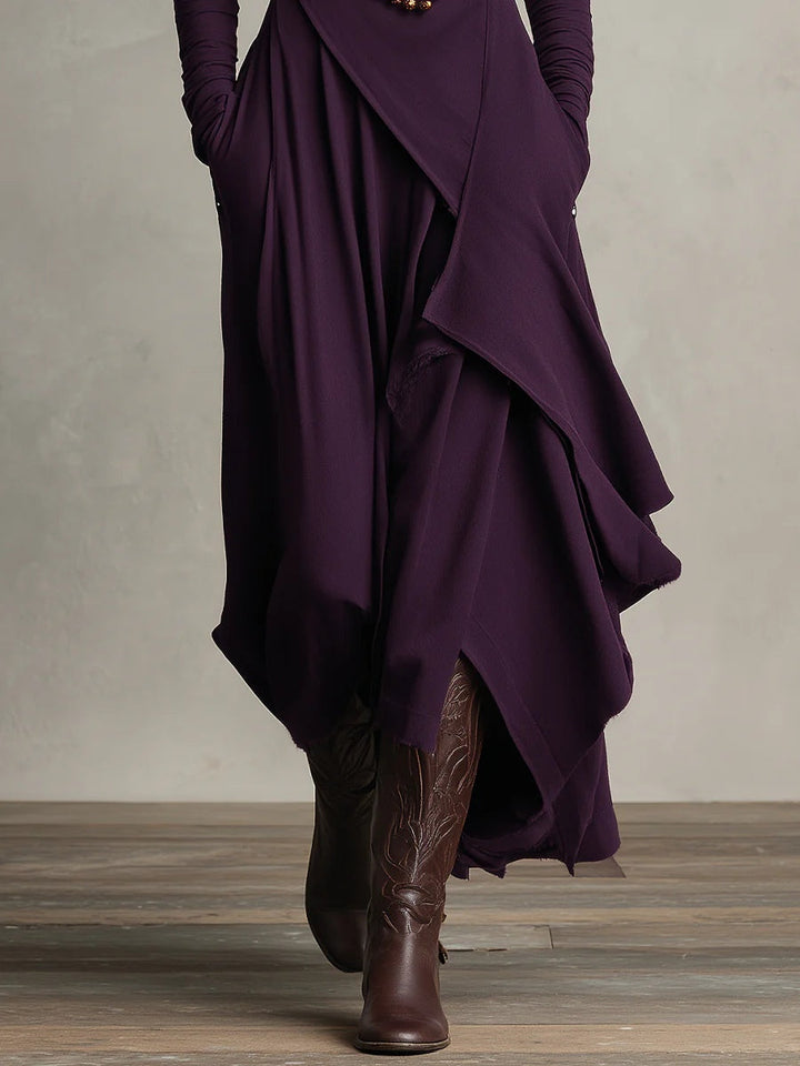 Detail of the plum asymmetric draped skirt panels over brown boots