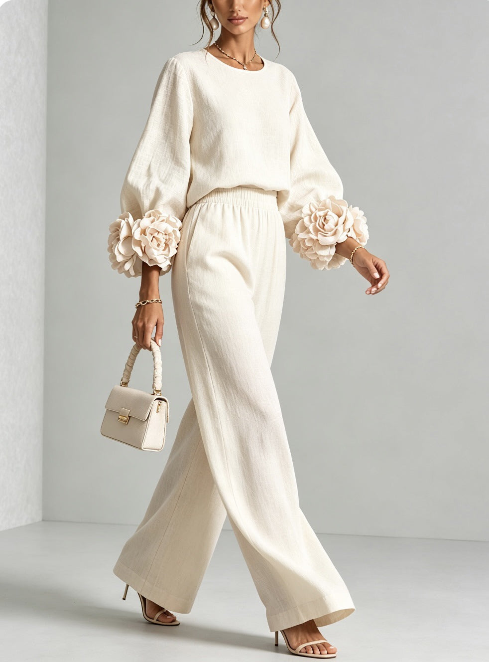 Cream knit top and wide leg pants walking, with a small white handbag