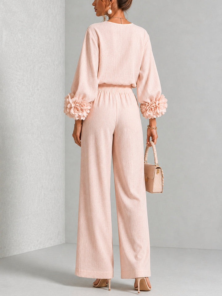Back view of the pink ruffle cuff top and wide leg pants with a small handbag