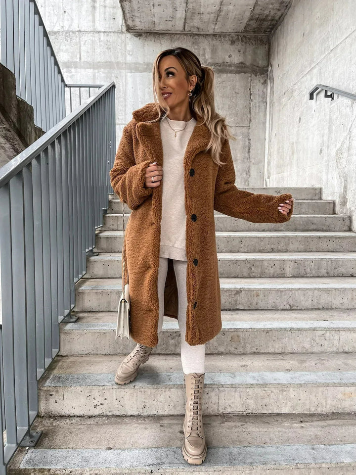Caramel teddy bear coat worn open over a white sweater and leggings