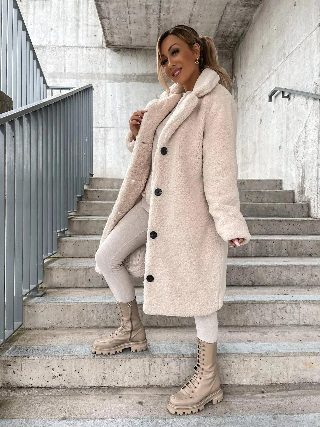 Cream long teddy coat with notch lapels, side angle on the steps