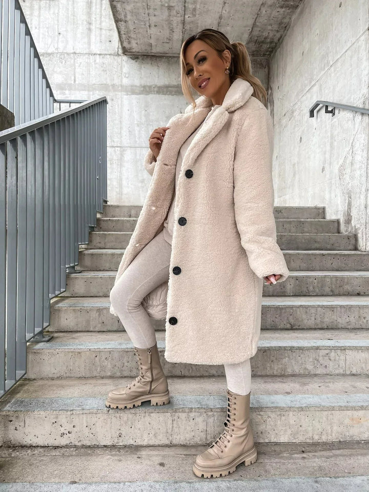 Cream long teddy coat with notch lapels, side angle on the steps