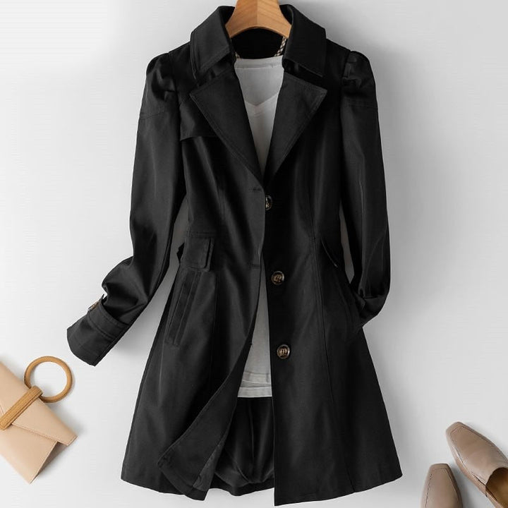Black mid length trench coat with button cuffs, front view with accessories