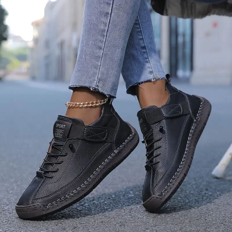 Women's walking shoes in black with strap and laces, worn with cuffed jeans
